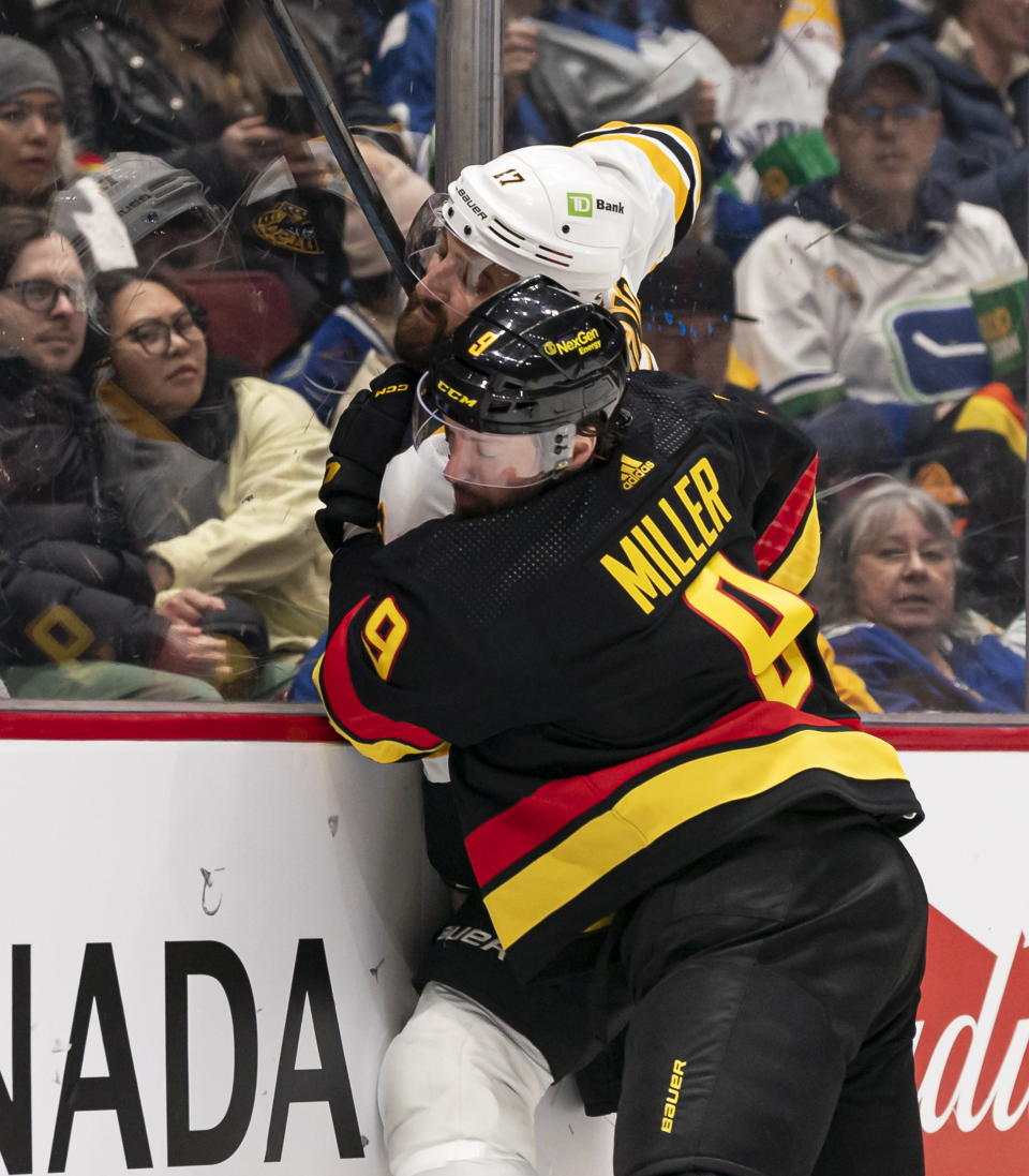 Vancouver Canucks' J.T. Miller hits Boston Bruins' Nick Foligno into the end boards during the second period of an NHL hockey game, Saturday, Feb. 25, 2023 in Vancouver, British Columbia. (Rich Lam/The Canadian Press via AP)