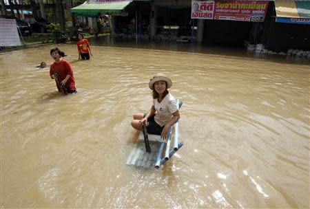 A woman sits on a bench in a flooded street at Srimahaphot district in Prachin Buri province, east of Bangkok September 24, 2013. REUTERS/Chaiwat Subprasom