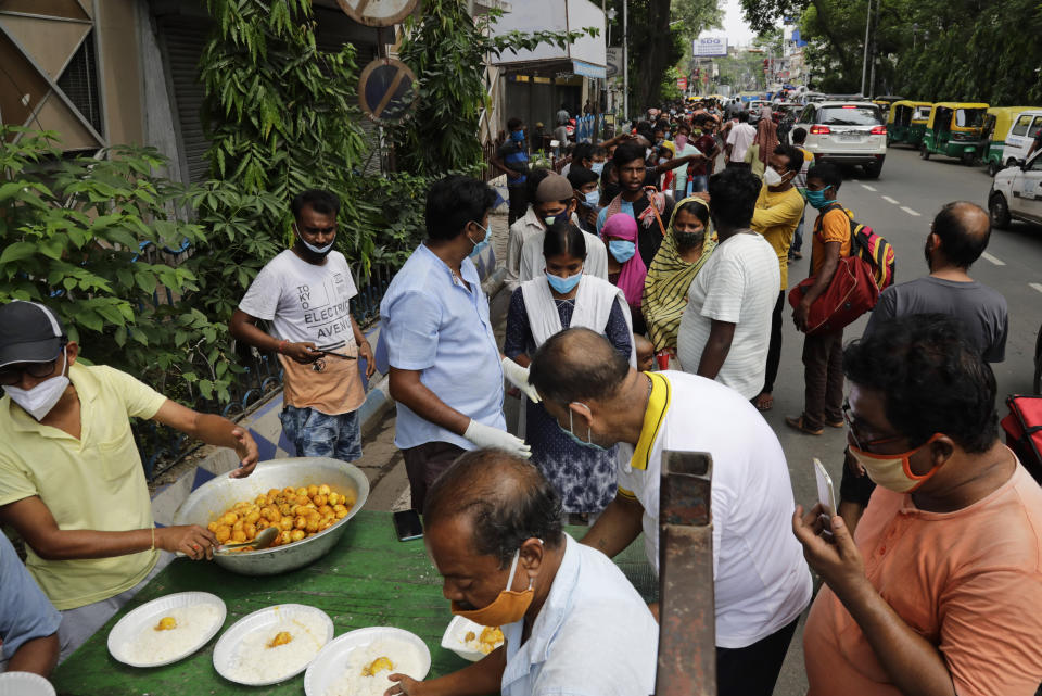 People line up to receive free food distributed by a voluntary organization during lockdown to curb the spread of the coronavirus pandemic in Kolkata, India, Wednesday, June 9, 2021. (AP Photo/Bikas Das)