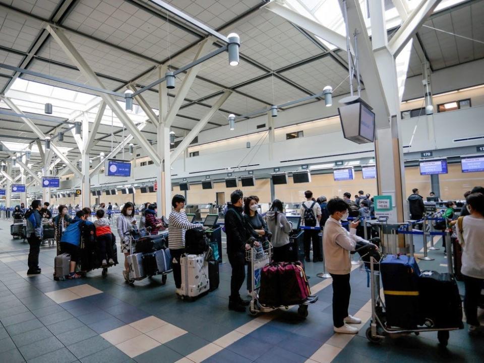 People standing in the check-in line at Vancouver International Airport.