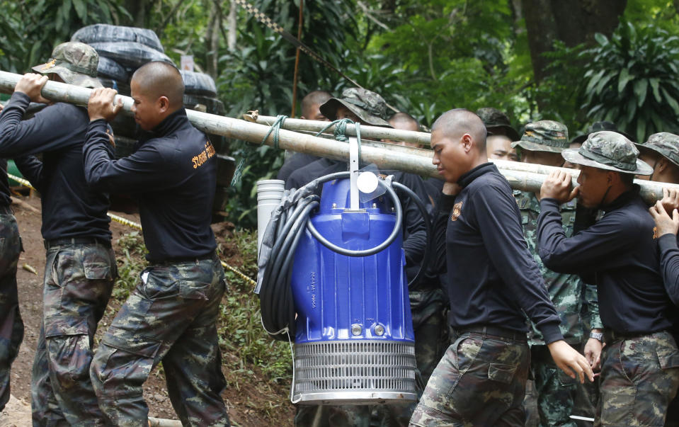 Soldiers carry a pump to help drain the rising flood water in a cave where 12 boys and their soccer coach have been trapped for two weeks. Source: AP Photo/Sakchai Lalit