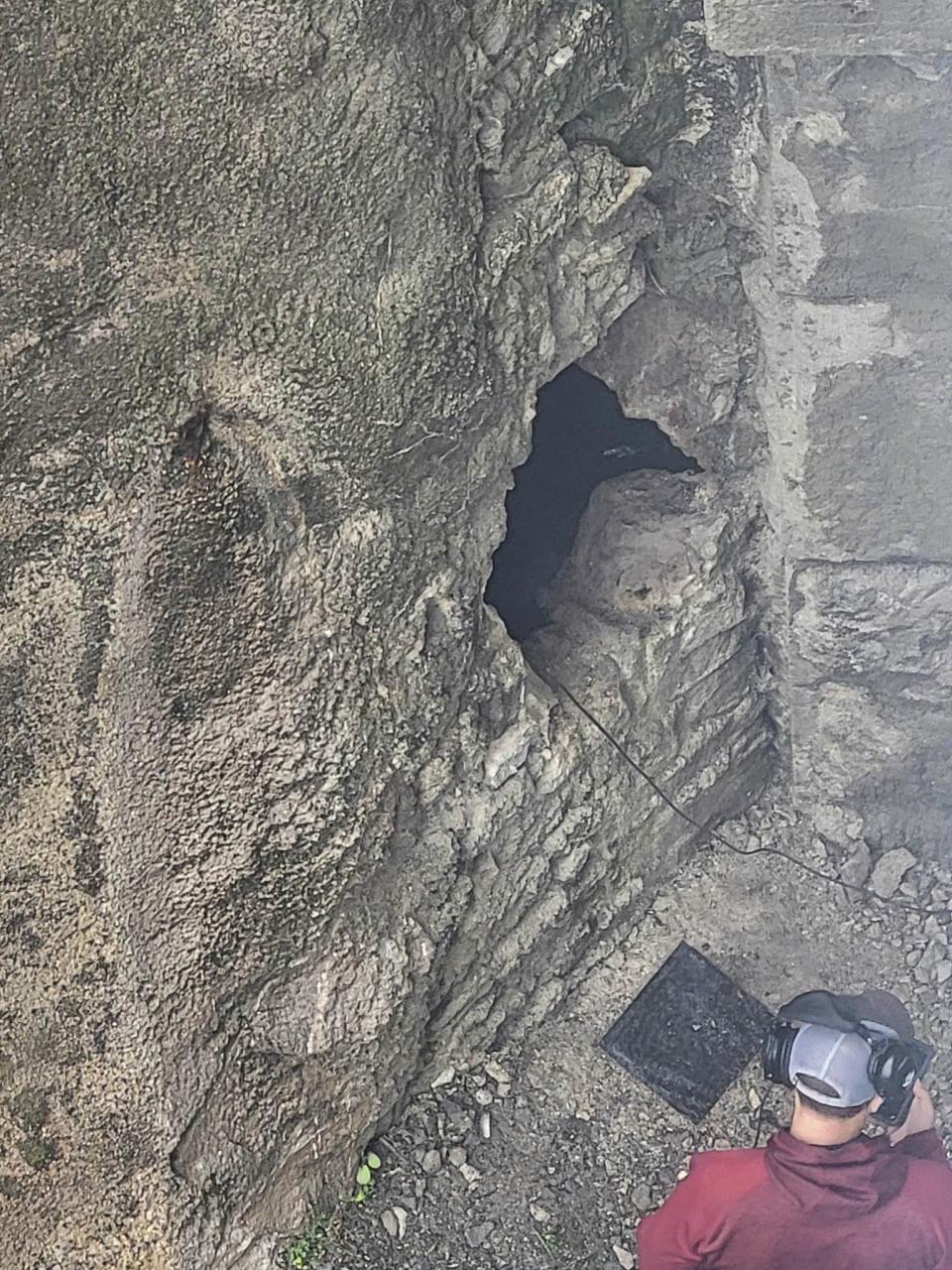 This photo provided by Jeremy Swiatowy shows rescue workers as they breach a wall with a sledgehammer, Monday, June 12, 2023, before shimming through the hole to help rescue people stuck inside the caves in Lockport, N.Y. One person was killed and multiple people were sent to local hospitals after a boat capsized on Monday, June 12, during a tour of an underground cavern system built to carry water from the Erie Canal beneath the western New York city of Lockport, officials said. (Jeremy Swiatowy via AP)