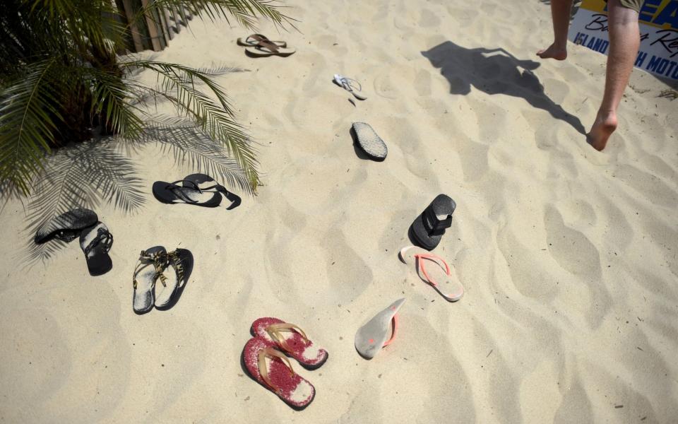 Flip flops are strewn on the sand outside a beachside restaurant - MARK MAKELA/Reuters