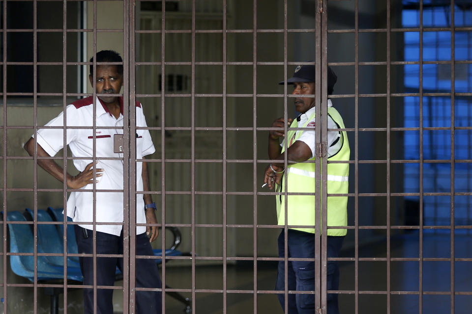 Security guards stand at the entrance to a hospital morgue in Seremban, Negeri Sembilan, Malaysia, Wednesday, Aug. 14, 2019. Malaysian police said Tuesday the family of missing 15-year-old London girl Nora Anne Quoirin has positively identified a naked body found near the nature resort where she disappeared over a week ago. (AP Photo/Lai Seng Sin)
