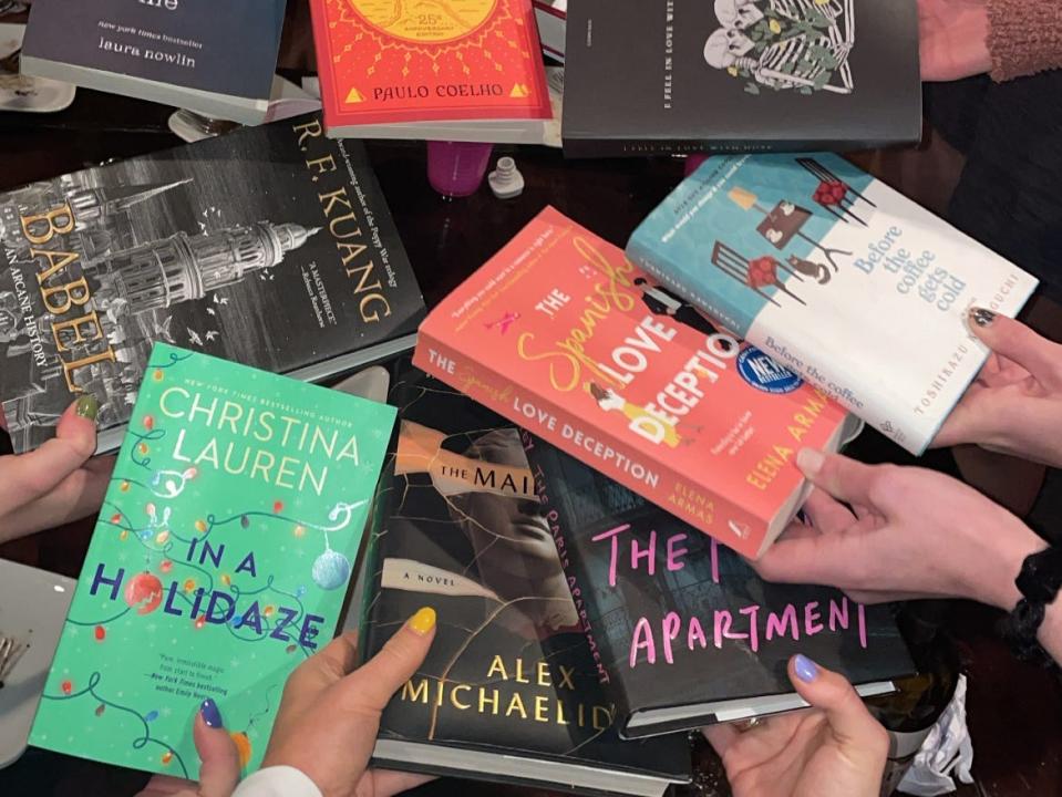 A group of people, each person holding a different book.