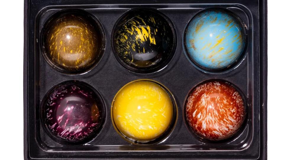 Six different round colorful chocolate truffles in a box