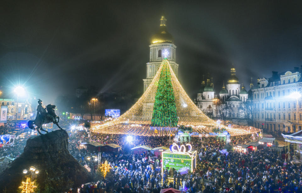 Crowds of people celebrate the New Year around the Christmas tree with the St. Sofia Cathedral in the background in Kyiv, Ukraine, early Friday, Jan. 1, 2021. Despite of COVID-19 quarantine restrictions, a lot of Ukrainians enjoy outdoor New Year events, often ignoring protective measures. (AP Photo/Efrem Lukatsky)