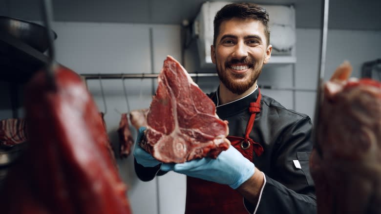 a proud butcher holding meat