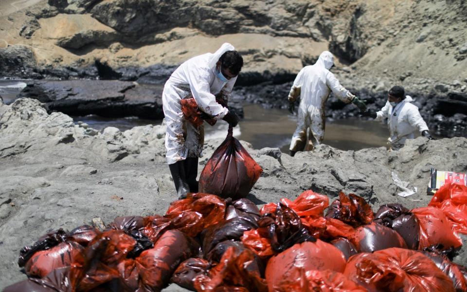 Locals in Ventanilla work to clear oil from the beach - REUTERS