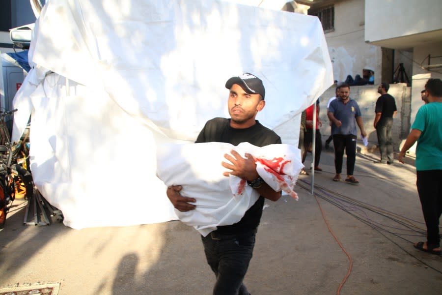 GAZA CITY, GAZA – OCTOBER 12: (EDITOR’S NOTE: Image depicts death) The body of a Palestinian killed during Israeli air strikes is carried in a sheet on October 12, 2023 in Gaza City, Gaza. At least 1,200 people, including at least 326 children, have been killed and more than 300,000 displaced, after Israel launched sustained retaliatory air strikes after a large-scale attack by Hamas. On October 7, the Palestinian militant group Hamas launched a surprise attack on Israel from Gaza by land, sea, and air, killing 1000 people and wounding more than 2000. Israeli soldiers and civilians have also been taken hostage by Hamas and moved into Gaza. The attack prompted a declaration of war by Israeli Prime Minister Benjamin Netanyahu. (Photo by Ahmad Hasaballah/Getty Images)