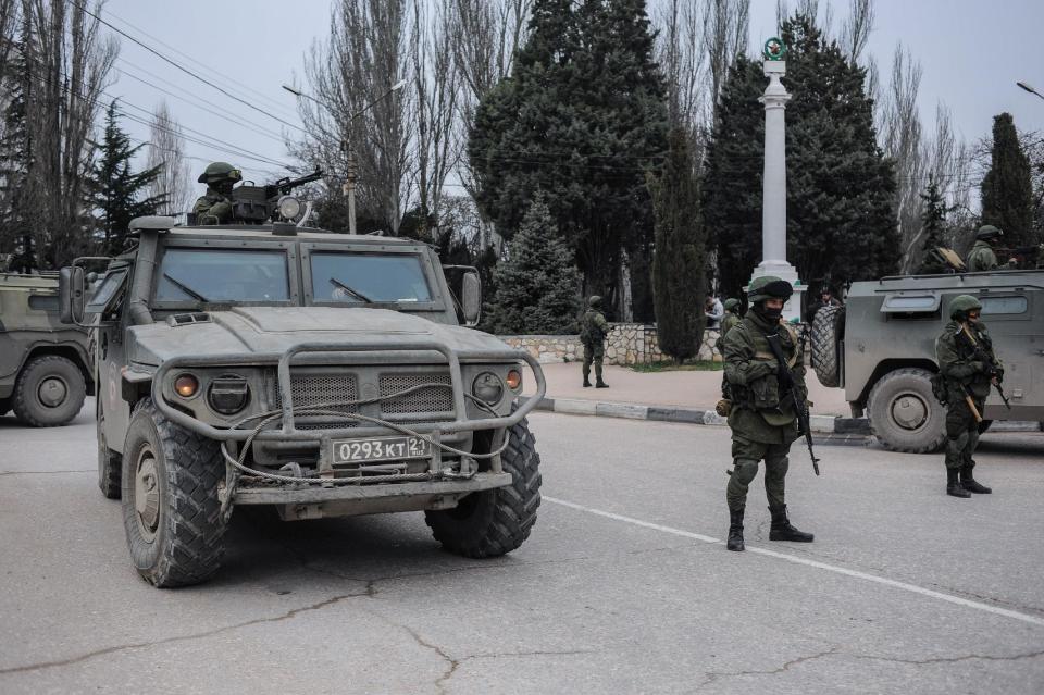 Troops in unmarked uniforms stand guard in Balaklava on the outskirts of Sevastopol, Ukraine, Saturday, March 1, 2014. An emblem on one of the vehicles and their number plates identify them as belonging to the Russian military. Ukrainian officials have accused Russia of sending new troops into Crimea, a strategic Russia-speaking region that hosts a major Russian navy base. The Kremlin hasn't responded to the accusations, but Russian lawmakers urged President Putin to act to protect Russians in Crimea. (AP Photo/Andrew Lubimov)