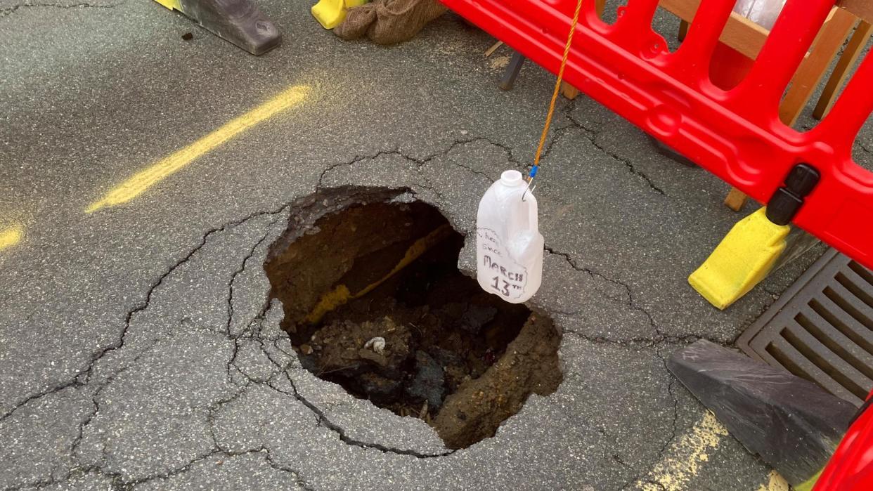A sinkhole in the surface of High Street, Ipswich, with a plastic bottle dangling over it