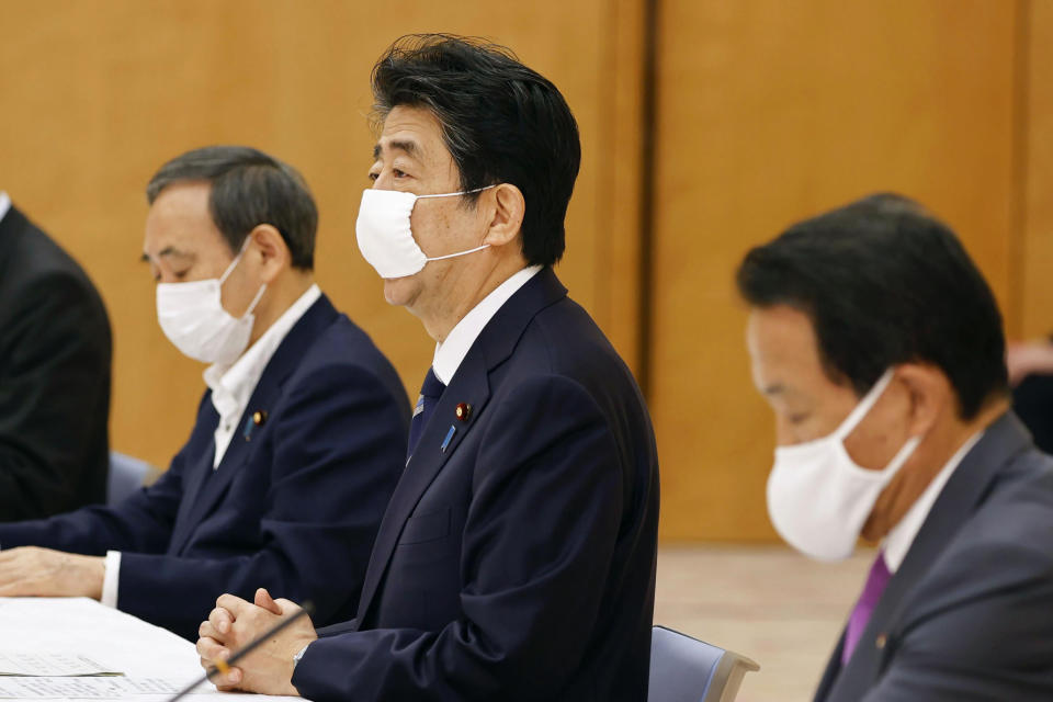 Japan's Prime Minister Shinzo Abe, center, speaks during a meeting of government and ruling party officials at his office in Tokyo Wednesday, May 27, 2020. Japan’s Cabinet has approved a proposed 32 trillion-yen ($296 billion) supplementary budget to help fund measures to cushion the blow to the economy from the coronavirus pandemic. (Kyodo News via AP)