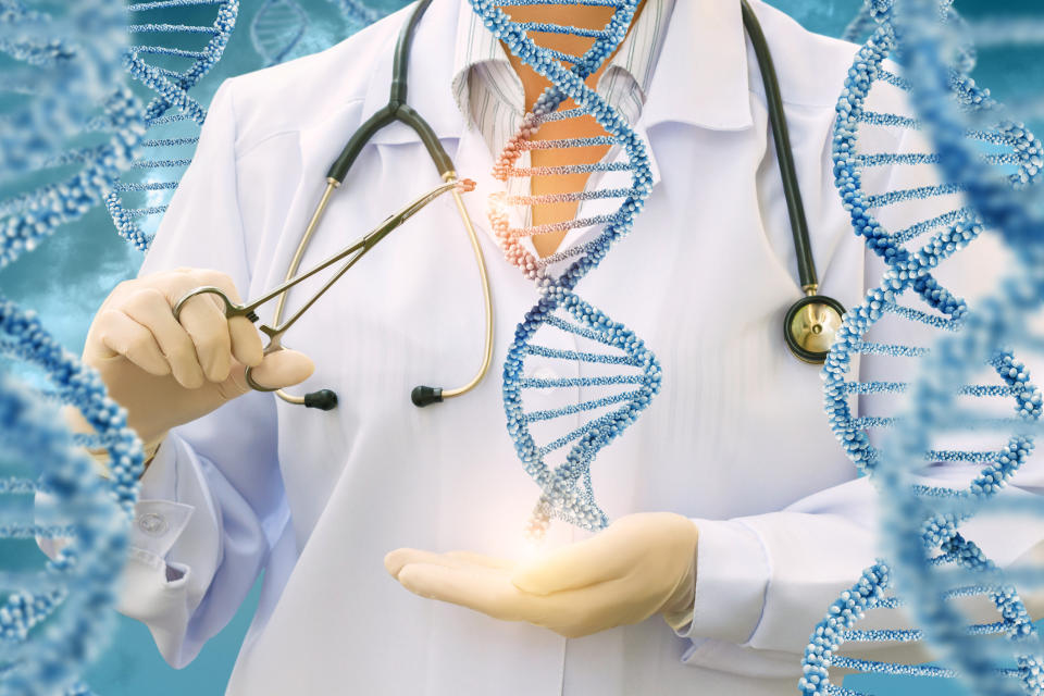 A person in a lab coat holds scissors while pretending to cut a piece of DNA.