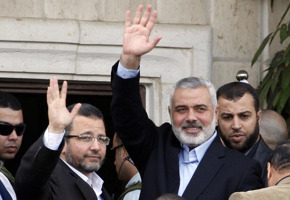 FILE - In this Friday, Nov. 16, 2012 file photo, Gaza's Hamas Prime Minister Ismail Haniyeh, right, and Egyptian Prime Minister Hesham Kandil, left, waves to the crowd as they meet in Gaza City. An Egyptian court ruled on Tuesday, March 4, 2014 to ban activities of the Palestinian militant group Hamas in Egypt in a move likely to fuel tension between Cairo's military-backed government and the Islamic group that rules the neighboring Gaza Strip. Egypt's interim leaders maintain that Hamas is playing a key role in the insurgency by militants in the northern region of the Sinai Peninsula, which borders Hamas-ruled Gaza and Israel. (AP Photo/Adel Hana, File)