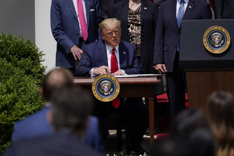 President Donald Trump signs the Paycheck Protection Program Flexibility Act during a news conference in the Rose Garden of the White House, Friday, June 5, 2020, in Washington. (AP Photo/Evan Vucci)