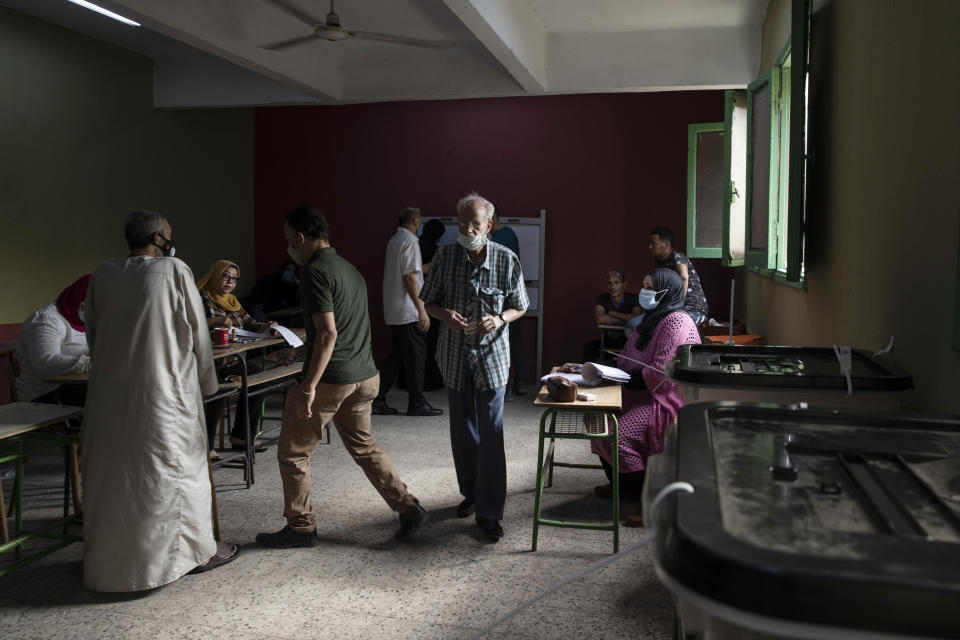 Election workers help people prepare to cast their ballots on the first day of the parliamentary election inside a polling station in Giza, Egypt, Saturday, Oct. 24, 2020. Egyptians began voting Saturday in the first stage of a parliamentary election, a vote that is highly likely to produce a toothless House of Representatives packed with supporters of President Abdel-Fattah el-Sissi. (AP Photo/Nariman El-Mofty)