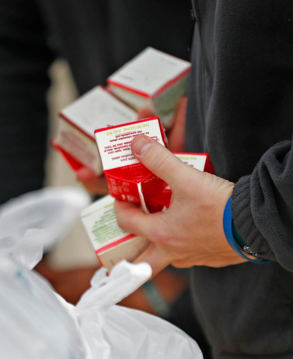 School staff and volunteers dole out milk as part of grab-and-go breakfasts and lunches free to students at Lawrence North High School on March 16 in Indianapolis.