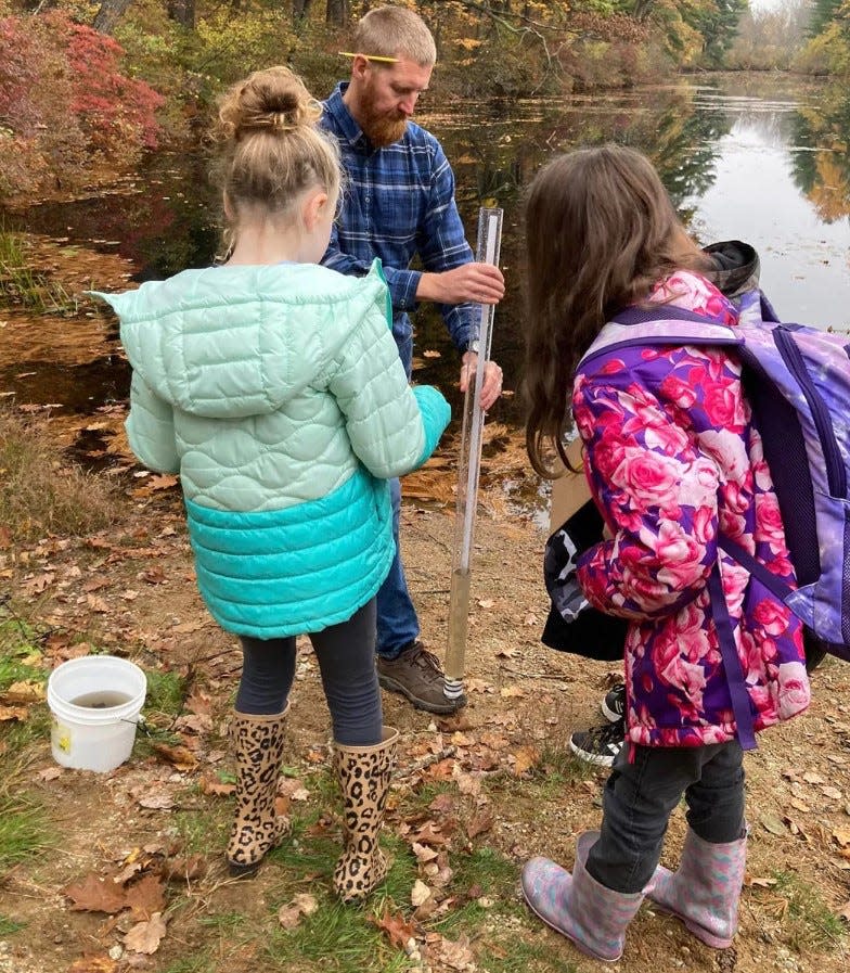 Students collect water samples from the Cocheco River as part of their yearlong project studying the life and health of the river.
