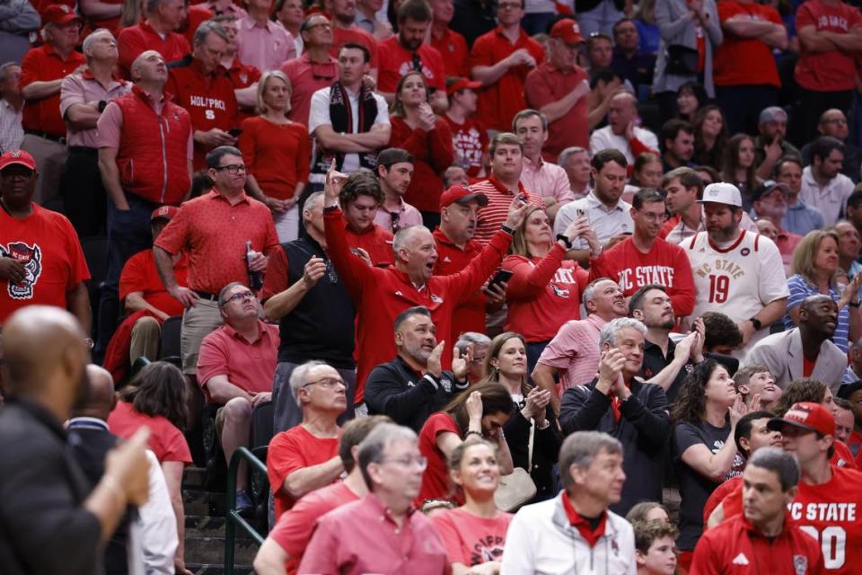 NC State football coach Dave Doeren (center) flashes the Wolfpack sign as he cheers for State against Duke in the NCAA Elite 8 game, Saturday, March 31, 2024.