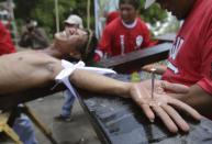 A Filipino devotee grimaces as he is nailed to a cross to re-enact the crucifixion of Jesus Christ in Santa Lucia village, Pampanga province, northern Philippines on Friday, April 18, 2014. Church leaders and health officials have spoken against the practice which mixes Roman Catholic devotion with folk belief, but the annual rites continue to draw participants and huge crowds. (AP Photo/Aaron Favila)