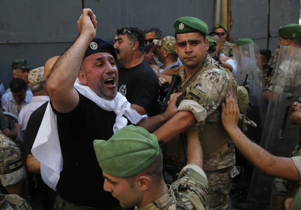 A Lebanese retired soldier, center, shouts slogans, as he tries with other protesters to enter the parliament building where lawmakers and ministers are discussing the draft 2019 state budget, in Beirut, Lebanon, Friday, July 19, 2019. Lebanese protesters rallying against an austerity budget have broken through a security cordon outside the parliament where lawmakers were voting on the controversial draft bill. The protesters, most of them veterans, pushed Friday barricades outside the parliament, walking over them and making their way closer to the heavily guarded parliament. (AP Photo/Hussein Malla)