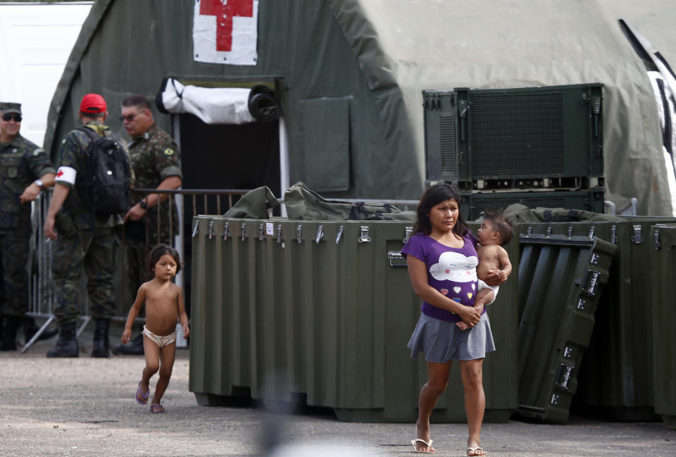 A Yanomami woman carrying a baby, walks next to an Army field hospital, on the grounds of the Saude Indigenous House, a center responsible for supporting and assisting Indigenous people in Boa Vista, Roraima state, Brazil, Wednesday, Jan. 25, 2023. The government declared a public health emergency for the Yanomami people in the Amazon, who are suffering from malnutrition and diseases such as malaria. (AP Photo/Edmar Barros)