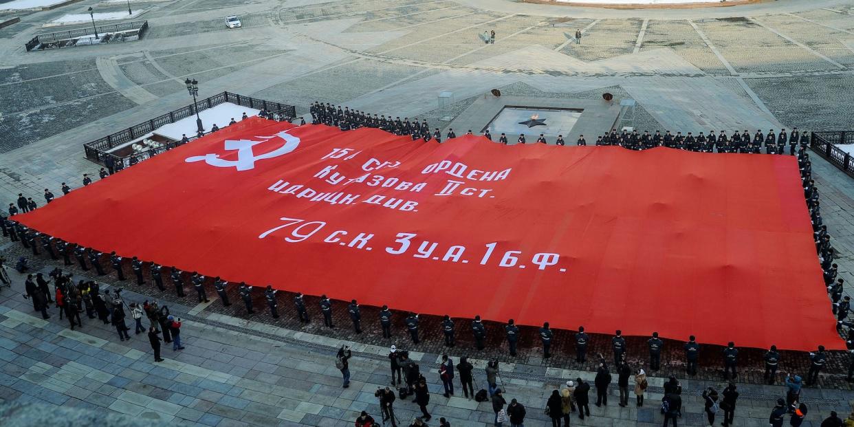 People hold a huge copy of the red Banner of Soviet Army's victory