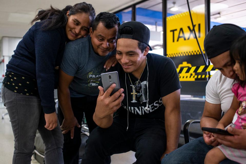 NEWARK, N.J. – Leydi Gonzalez, 29, from left, and Jaime Escalante Galvez, 35, watch videos with her brother, Abner Gonzalez, 22, at Newark Liberty International Airport.