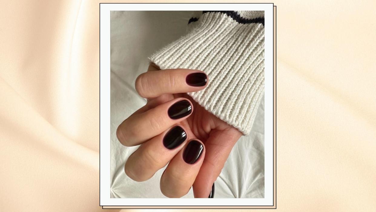  close up of woman's hand wearing dark red nails 