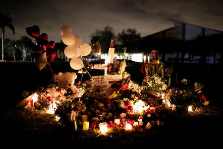 Pictures of Joaquin Oliver and Aaron Feis, victims of the mass shooting at Marjory Stoneman Douglas High School, are seen on a cross placed in a park to commemorate the victims, in Parkland, Florida, U.S., February 19, 2018. REUTERS/Carlos Garcia Rawlins