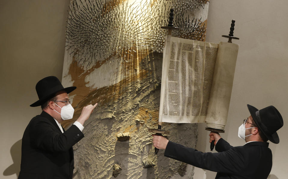 Rabbi Shaul Nekrich, right, holds the Sulzbach Torah Scroll in a ceremony at the Reichstag building in Berlin, Germany, Wednesday, Jan. 27, 2021 to complete the historic Sulzbach Torah Scroll from 1792, rediscovered in 2013 and just restored. The ceremony takes place on the International Holocaust Remembrance Day. (Odd Andersen/Pool Photo via AP)