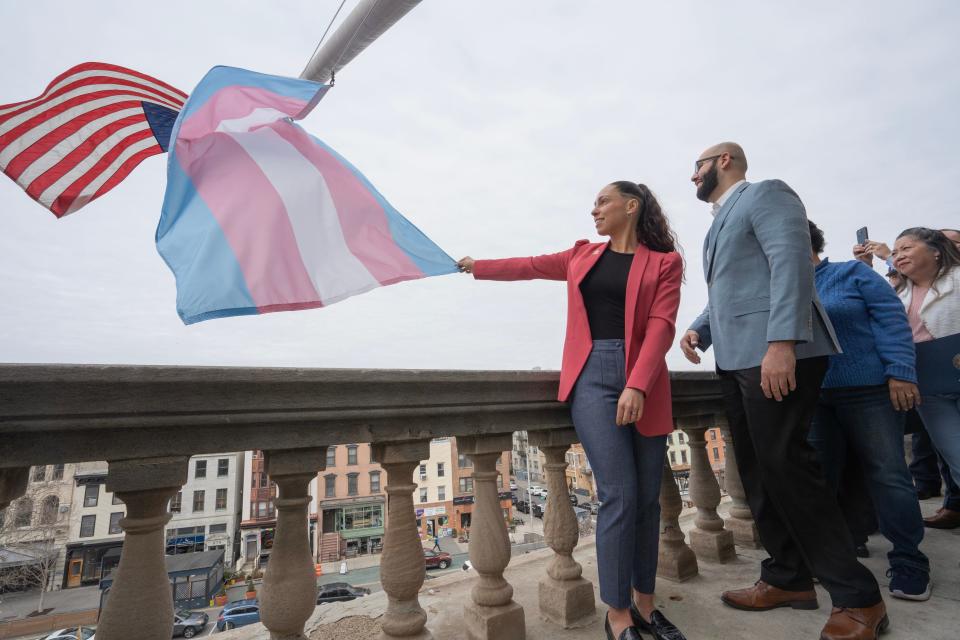 Elizabeth Schedl, executive director of Hudson Pride Center, hold onto the Transgender Pride Flag as it is hoisted up the flag pole.  The Jersey City Mayor's office and the Mayor's LGBTQ+ Task Force raise the Transgender Pride Flag at a ceremony marking Trans Day of Visibility in Jersey City, NJ on Friday March 31, 2023. 