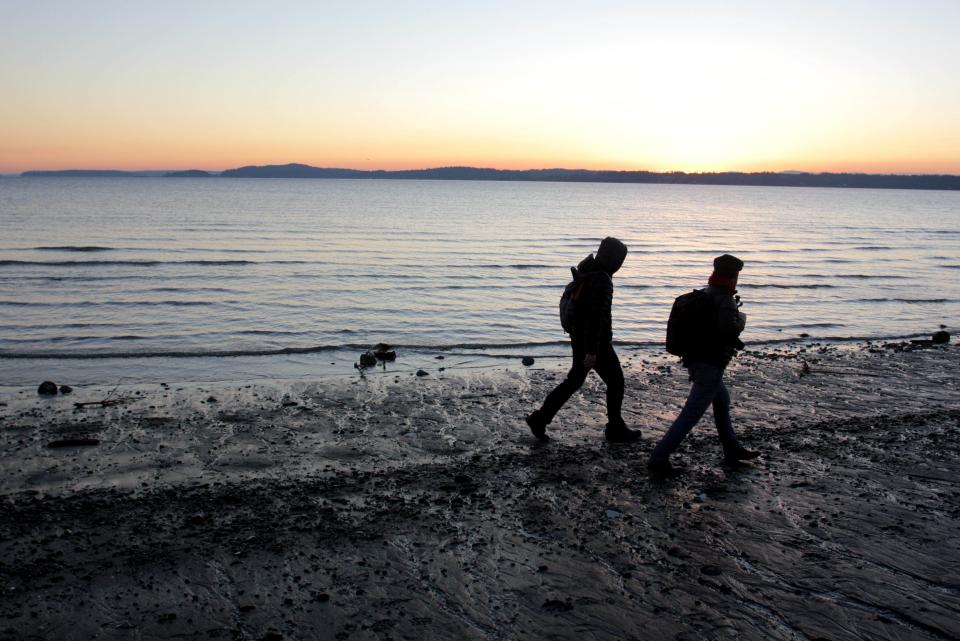 In this image taken Jan. 16, 2013, two people walk the beach at Discovery Park in Seattle. At 534 acres, Discovery Park is the largest park in the city and it features seaside bluffs, views of the Puget Sound, trails, a light house and a beach. (AP Photo/Manuel Valdes )