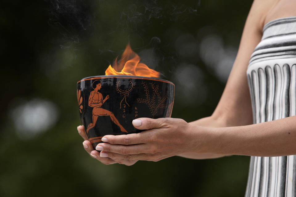 A performer holds a ceramic pot with the flame during the official ceremony of the flame lighting for the Paris Olympics, at the Ancient Olympia site, Greece, Tuesday, April 16, 2024. The flame will be carried through Greece for 11 days before being handed over to Paris organizers on April 26. (AP Photo/Thanassis Stavrakis)