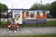 Lottie Gray sits on a wagon as she waits for a Houston Independent School District food distribution site to open Monday, April 6, 2020, in Houston. HISD relaunched their food distribution efforts throughout the district Monday, with a streamlined process that will implement increased safety measures. (AP Photo/David J. Phillip)