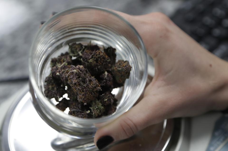 A person holds a container with marijuana buds at the Far West Holistic Center dispensary, Wednesday, Nov. 7, 2018, in Detroit. Michigan voters have made their state the first in the Midwest to legalize recreational marijuana, passing a ballot measure that will allow people 21 or older to buy and use the drug and putting conservative neighboring states on notice. (AP Photo/Carlos Osorio)