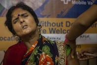 An Indian woman reacts as she gets inoculated agains the coronavirus in Gauhati, India, Thursday, Oct. 21, 2021. India has administered 1 billion doses of COVID-19 vaccine, passing a milestone for the South Asian country where the delta variant fueled its first crushing surge this year. (AP Photo/Anupam Nath)