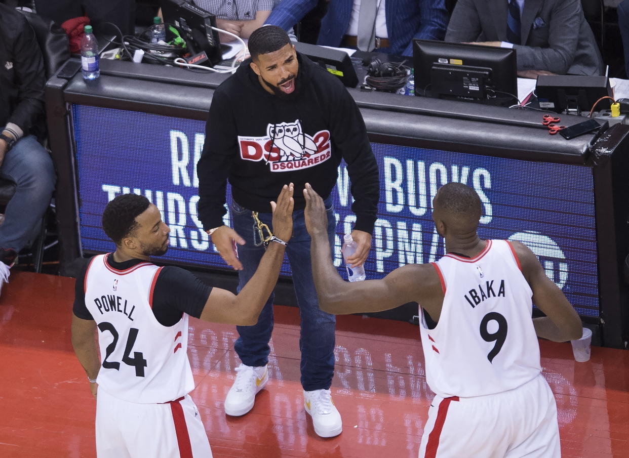 Toronto Raptors forward Norman Powell (24) and center Serge Ibaka (9) celebrate with Drake, center, during the second half of Game 4 of the team's NBA basketball playoffs Eastern Conference finals against the Milwaukee Bucks, Tuesday, May 21, 2019, in Toronto. (Nathan Denette/The Canadian Press via AP)