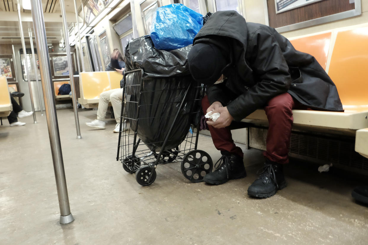 A homeless man sleeps in a subway car