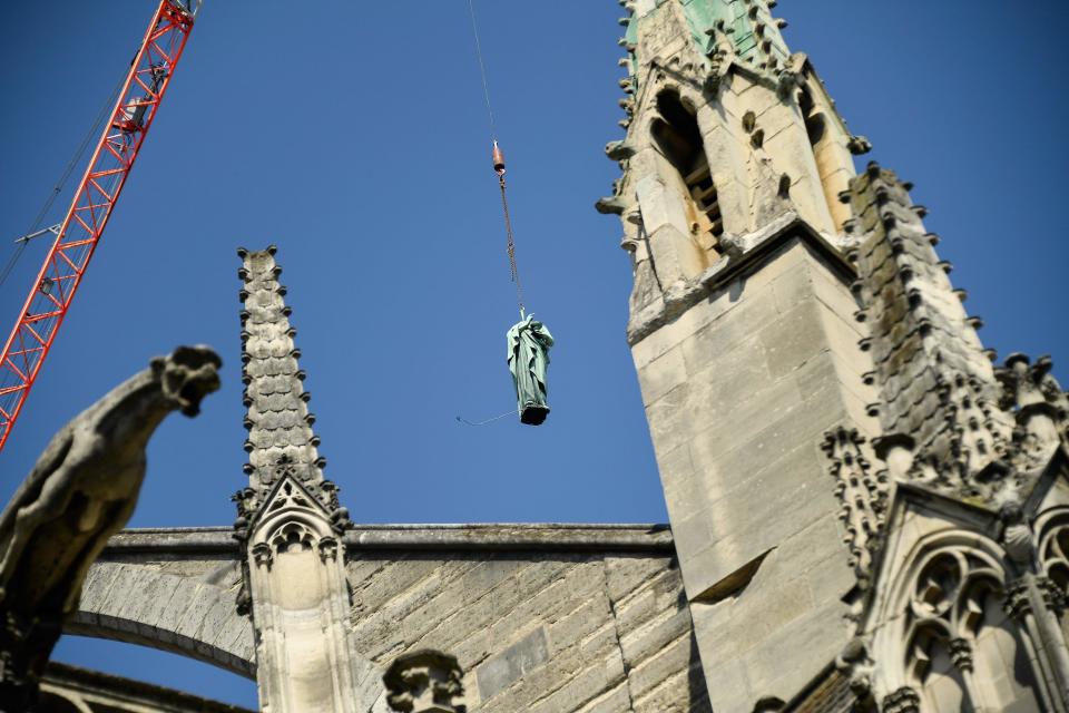 A crane lifts one of 16 copper statues off Notre-Dame-de-Paris Cathedral to be taken for restoration on April 11, 2019, before a devastating fire on April 15, 2019. The statues of the 12 apostles and the 4 evangelists sit around the spire of the cathedral.