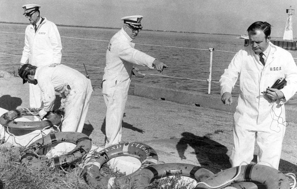 Coast guard officers stand over life rings