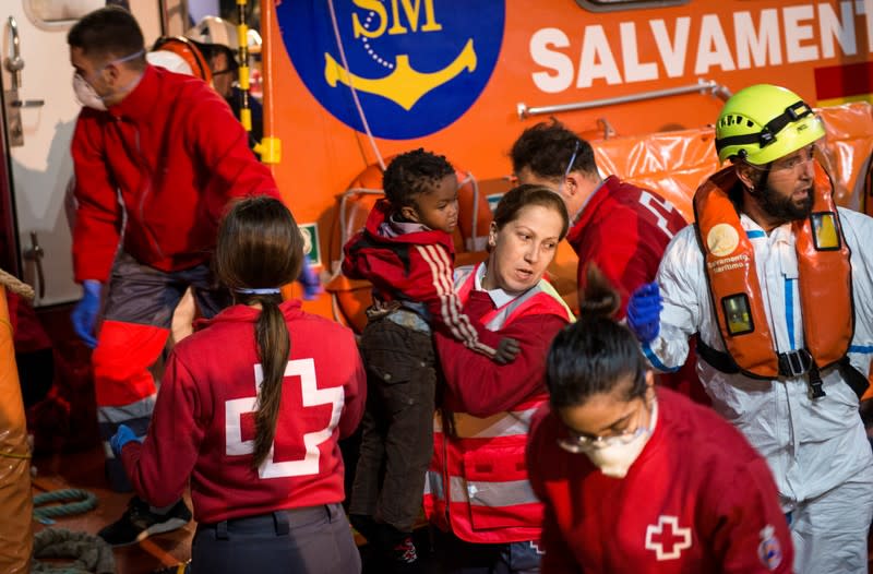 Members of the Spanish Red Cross help migrants disembark the ship after dozens of them were rescued in a raft off the coast at the Mediterranean Sea, at the port of the Spanish North African enclave of Melilla