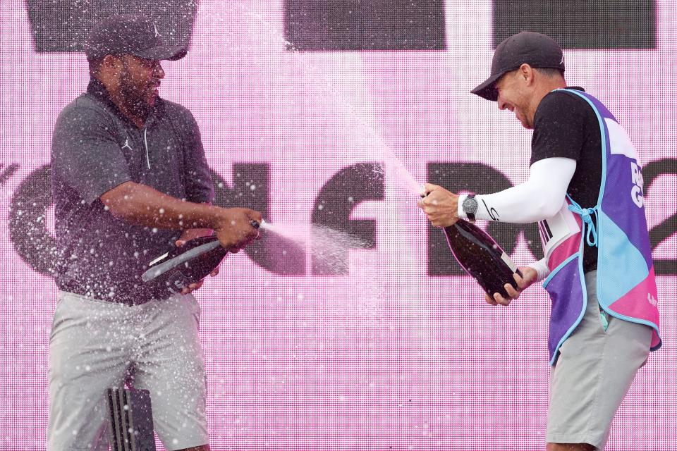 May 28, 2023; Potomac Falls, Virginia, USA; Harold Varner III (L) and caddie Chris Rice (R) celebrate on the podium after winning the individual championship of LIV Golf Washington, D.C. golf tournament at Trump National. Mandatory Credit: Geoff Burke-USA TODAY Sports