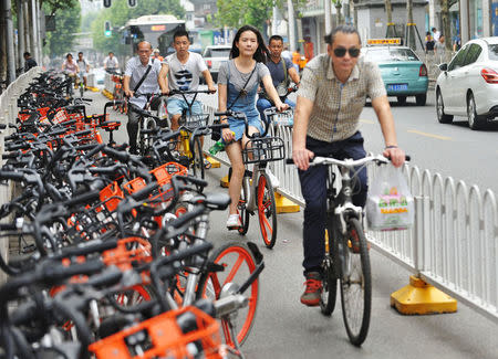 People ride past shared bikes at a bike lane in Wuhan, Hubei province, China June 26, 2017. REUTERS/Stringer