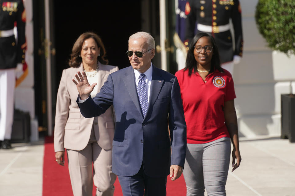 FILE - President Joe Biden waves as he arrives with Vice President Kamala Harris and Lovette Jacobs, a fifth-year IBEW Local 103 electrical apprentice in Boston, during a ceremony about the Inflation Reduction Act of 2022, on the South Lawn of the White House in Washington, Sept. 13, 2022. It's a once-in-a-generation undertaking, thanks to three big bills approved by Congress last session. They're now coming online. Biden calls it "Bidenomics." Republicans criticize it as big government overreach. Taken together, the estimated $2 trillion is a centerpiece of Biden's re-election effort. (AP Photo/Andrew Harnik)