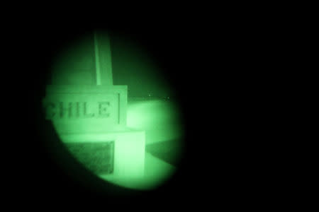 A milestone is seen using a night vision device during a police patrol at a restricted mined area, at the Chilean and Peruvian border in Arica, Chile, November 15, 2018. REUTERS/Ivan Alvarado