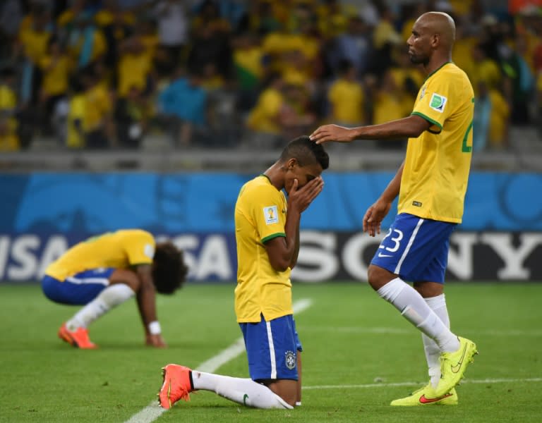 Brazil's midfielder Luiz Gustavo (C) is consoled by teammate Maicon after defeat in the semi-final football match between Brazil and Germany on July 8, 2014, during the 2014 FIFA World Cup