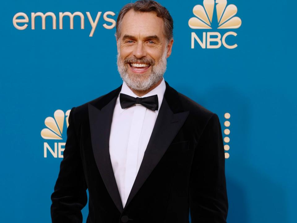 Murray Bartlett poses for photos on the Emmys red carpet in a black tuxedo.