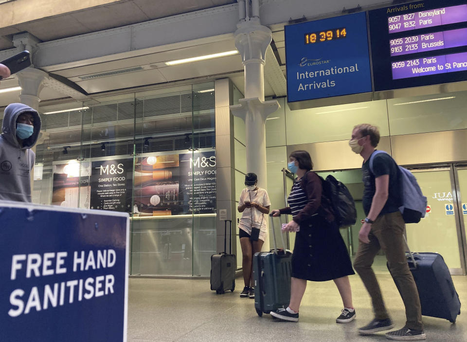 Travellers emerge from the Eurostar St Pancras International railway station, returning from France Friday Aug. 14, 2020, to avoid the quarantine restrictions. Travellers have to return to the UK before the 4.00 am Saturday deadline, to avoid new quarantine regulations imposed on people returning from France because of the coronavirus. (Kirsty O'Connor/PA via AP)